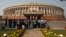 FILE - People stand in front of the Indian parliament building on the opening day of the winter session in New Delhi, Nov. 22, 2012. 