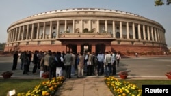 FILE - People stand in front of the Indian parliament building on the opening day of the winter session in New Delhi, Nov. 22, 2012. 