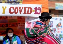 A Bolivian woman walks past a stand that provides information about COVID-19, as authorities have started to vaccinate people who make a living crossing the border between Bolivia and Peru, in Desaguadero, Bolivia, May 21, 2021.
