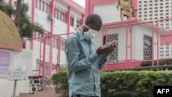 FILE - A man wears a mask while walking outside the entrance to the Yaounde General Hospital in Yaounde, March 6, 2020.