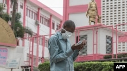 FILE - A man wears a mask while walking outside the entrance to the Yaounde General Hospital in Yaounde, March 6, 2020.
