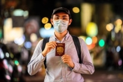 In this photo taken in Hong Kong on June 3, 2020, Reese Tan, a 25-year old tutor, poses in his favorite part of the city, the bustling shopping and eating district of Mongkok.