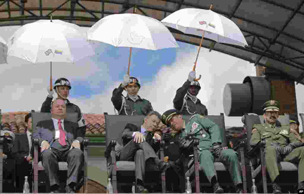 Colombia&#39;s President Juan Manuel Santos, center left, leans in to listen to Colombia&#39;s Armed Forces Commander Gen. Juan Pablo Rodriguez, during a military ceremony in Bogota, Colombia.