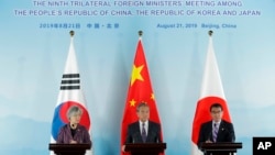 资料照片：2019年8月21日，中国外长王毅(中)、韩国前外长康京和(左)、日本前外相河野太郎在北京举行三国外长会谈后出席联合记者招待会。（美联社）