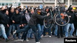 A man throws a bicycle during a demonstration by 'hooligans against Salafists and Islamic State extremist' in Cologne, Germany, Oct. 26, 2014. 