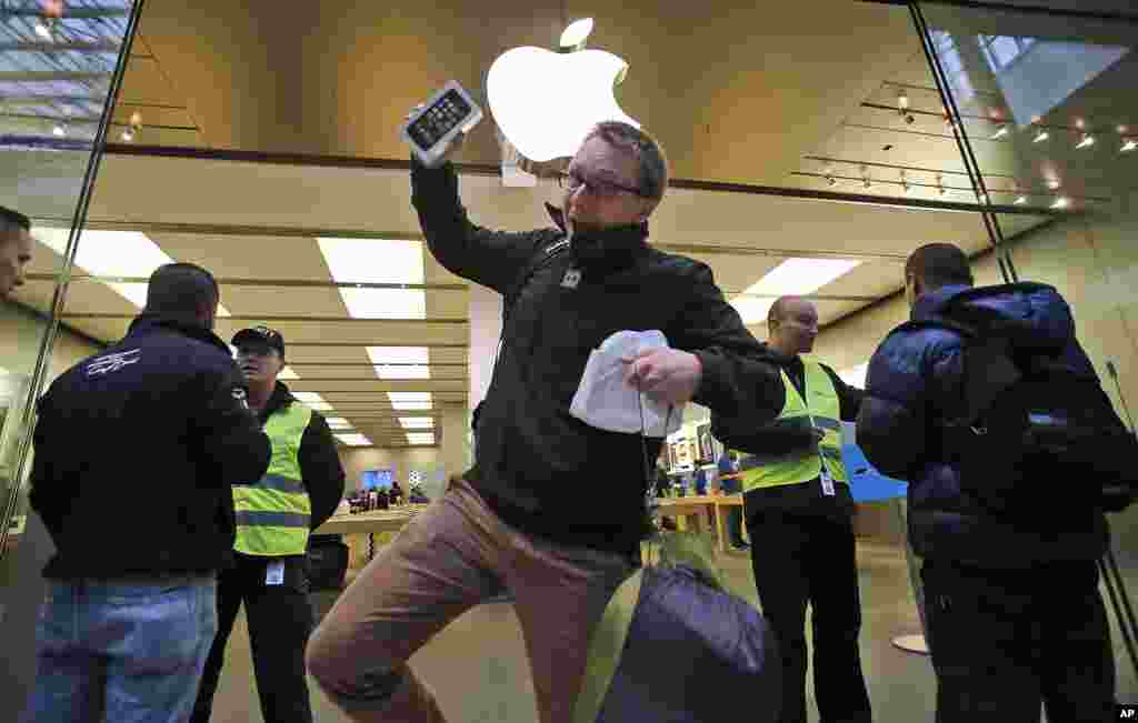 A customer celebrates with the new iPhone 5S as he leaves the Apple store in Oberhausen at the start of the new iPhone sale in Oberhausen, Germany. 