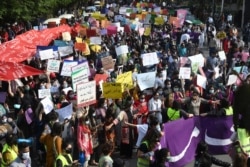 FILE - Activists of the Aurat March carry placards as they march during a rally to mark International Women's Day in Lahore, March 8, 2021.