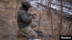 FILE - A Ukrainian serviceman of 47th brigade prepares a Starlink satellite internet system at a front line near the town of Avdiivka in Donetsk region, Ukraine, Feb. 20, 2024.