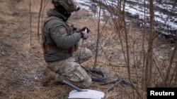 FILE - A Ukrainian service member prepares a Starlink satellite internet system at his positions at a front line near the town of Avdiivka in Ukraine's Donetsk region, Feb. 20, 2024. 