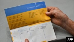 A woman shows her vaccination record at Zinga Zanga village hall vaccination centre in Beziers, southern France, on March 17, 2021.