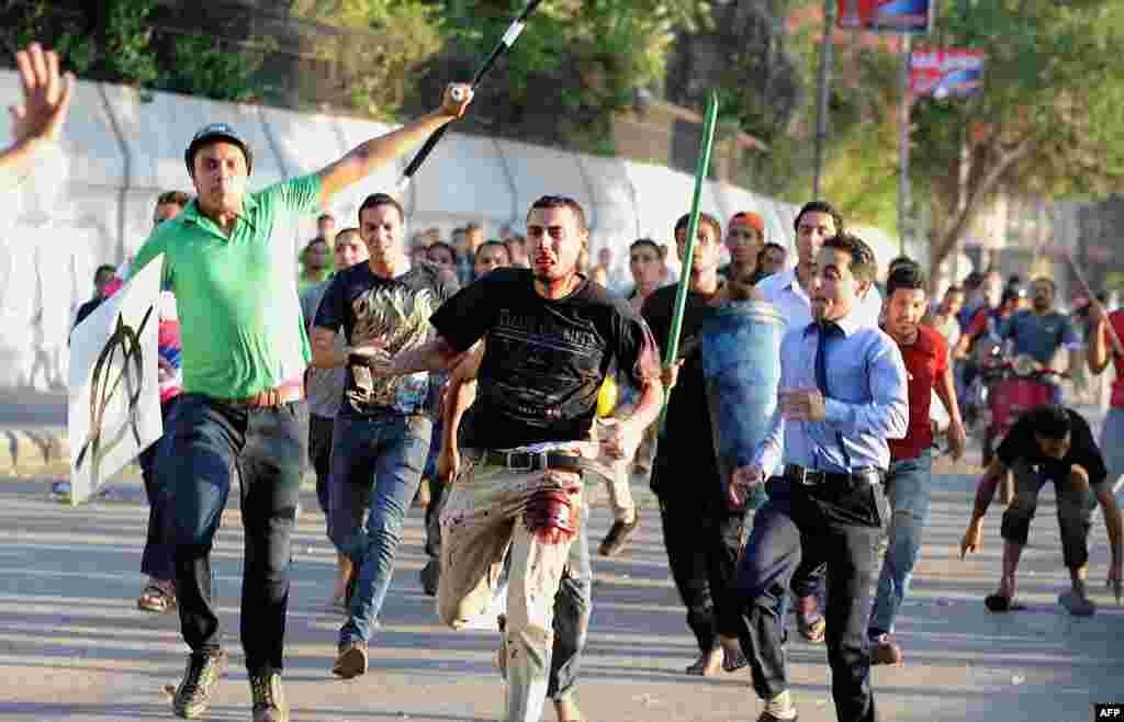 A supporter of ousted Egyptian President Mohamed Morsi is beaten by pro-government and army supporters during clashes that erupted at Tahrir Square and around the US Embassy in Cairo, July 22, 2013. 