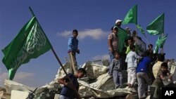 Israeli Arab youths, holding green Islamic flags, stand on the rubble of a mosque, demolished by the Israeli police, in the Bedouin city of Rahat, southern Israel, Sunday, Nov. 7, 2010.