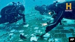 In this photo provided by the HISTORY® Channel, underwater explorer and marine biologist Mike Barnette and wreck diver Jimmy Gadomski explore a 20-foot segment of the 1986 Space Shuttle Challenger. (The HISTORY® Channel via AP)