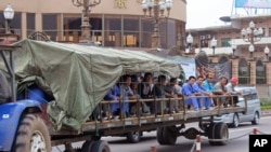 FILE - In this photo taken on May 20, 2015, Chinese workers travel on the back of a trailer pulled by a tractor on their way to work in Kinshasa, Democratic Republic of Congo.