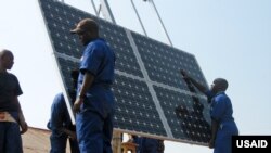 FILE -Workers are trained to install solar panels at a health clinic in Rwanda, Nov. 10, 2010.