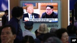 People watch a TV screen showing file footage of U.S. President Donald Trump, left, and North Korean leader Kim Jong Un during a news program at the Seoul Railway Station in Seoul, South Korea, May 16, 2018.