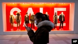 FILE - A woman walks past mannequins promoting a sale outside a retail outlet in Beijing, China, Dec. 16, 2016. China’s economic growth ticked up in the final quarter of 2016, but its full-year performance was the weakest in three decades.