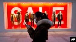 FILE - A woman walks past mannequins promoting a sale outside a retail outlet in Beijing, China, Dec. 16, 2016. China’s economic growth ticked up in the final quarter of 2016, but its full-year performance was the weakest in three decades.