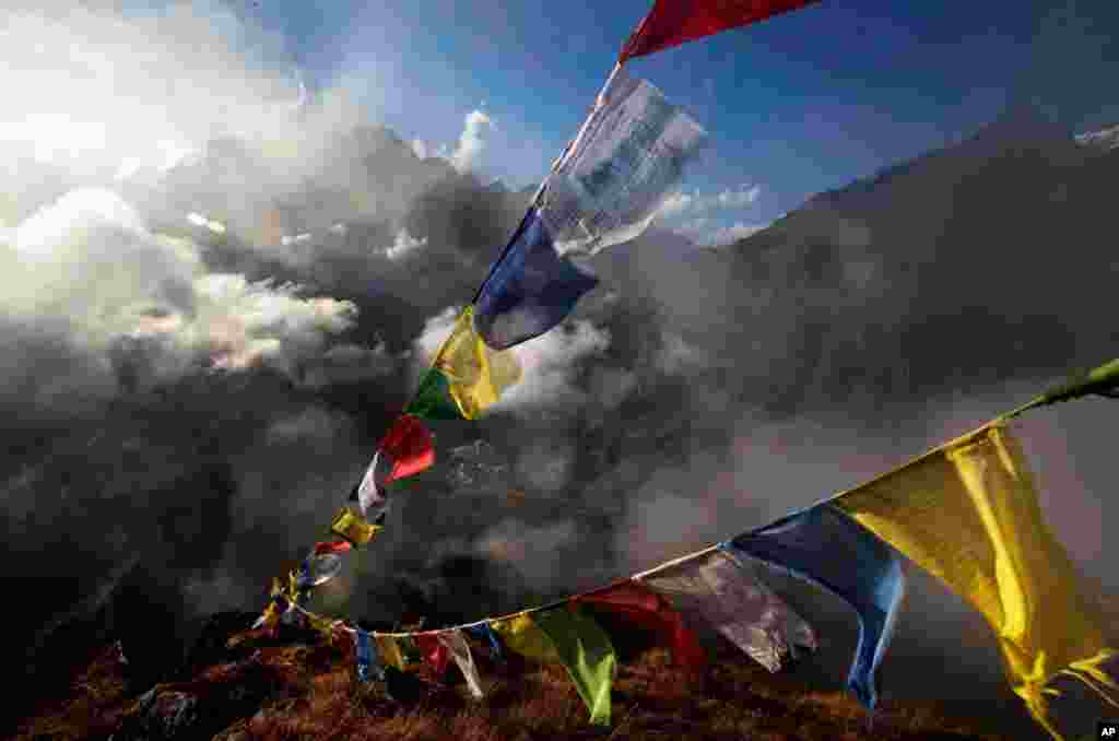 October 26: Tibetan Buddhist prayer flags fly over Tengboche, in the Himalaya's Khumbu region, Nepal. (AP Photo/Kevin Frayer)
