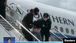 People being deported from Thailand are seen brought off an airplane by police at an unidentified location in China on July 9, 2015 in this still image taken from CCTV video aired on July 11, 2015. CCTV said they were mostly from the country's western, X