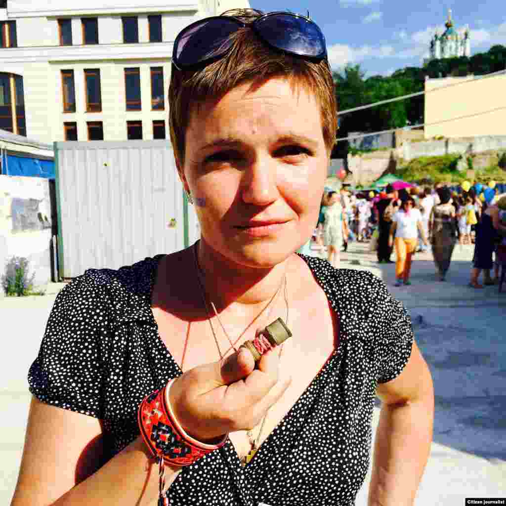 Lesya Litvinova shows a rubber bullet that she wears to remind herself why she is a volunteer,&nbsp;​June 3, 2015. (Daniel Schearf/VOA)