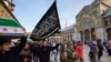 FILE - A masked opposition fighter carries a flag of Hayat Tahrir al-Sham in the courtyard of the Umayyad Mosque in the old walled city of Damascus, Syria, Dec. 10, 2024.