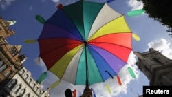A person holds an umbrella with colored condoms in London, September 18, 2010