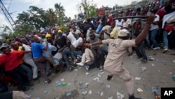 Police officer beats back supporters of Haiti's former President Jean-Bertrand Aristide outside courthouse, Port-au-Prince, May 8, 2013.