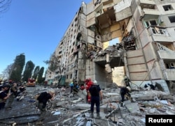 Firefighters and rescuers work at the site of an apartment building hit by a Russian air strike during Russia's attack on Kharkiv, Ukraine, Sept. 24, 2024.