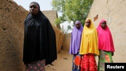 FILE - Amina Usman (L), a 15-year-old student, who was among those who escaped the attack on her school, stands with her sisters in Dapchi, Nigeria, Feb. 23, 2018.