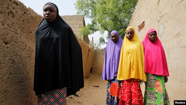 FILE - Amina Usman (L), a 15-year-old student, who was among those who escaped the attack on her school, stands with her sisters in Dapchi, Nigeria, Feb. 23, 2018.