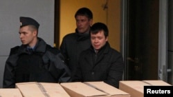 Detained opposition activist Konstantin Lebedev (R, front) is escorted out of a building of the Russian Investigative Committee in Moscow, Oct. 17, 2012.