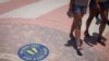 Bañistas caminan junto a una señal en el piso que indica mantener el distanciamiento social para evitar el contagio de coronavirus en Miami Beach, Florida. Junio 10, 2020.