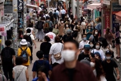 People wearing face masks to help curb the spread of the coronavirus walk through a shopping area in Tokyo, July 3, 2020. Japan lifted a seven-week pandemic state of emergency in late May.