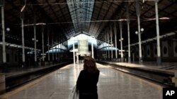 A woman looks at a sign announcing the disruption of train services at an empty Rossio train station in Lisbon, November 24, 2011.