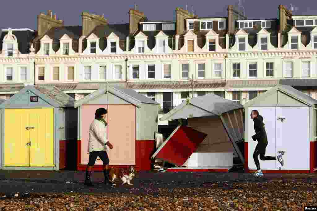 People pass by a beach hut destroyed by a recent storm on the promenade in Brighton, in southern England.