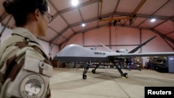 FILE - A French soldier of the regional anti-insurgent Operation Barkhane stands in front of a General Atomics MQ-9 Reaper drone version Block 1 in Niamey, Niger, Oct. 21, 2017.