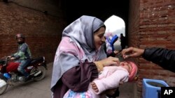 A health worker administers a polio vaccine to a child in a neighborhood of Lahore, Pakistan, Jan. 25, 2022.