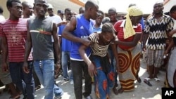 Neighbors help lead away a woman after she collapsed in grief as she visited the local opposition party office where her brother was killed in an overnight attack, in the Yopougon neighborhood of Abidjan, Ivory Coast, 02 Dec 2010