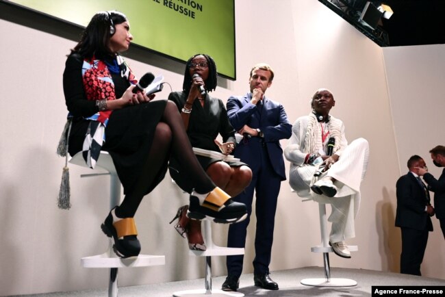 FILE - French President Emmanuel Macron, center, listens during a conference about restitutions of African heritage during a conference at the Benin stand during the Africa-France summit in Montpellier, southern France, Oct. 8, 2021.