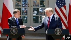FILE - President Donald Trump and Polish President Andrzej Duda reach to shake hands at a news conference in the Rose Garden of the White House, in Washington, June 12, 2019.