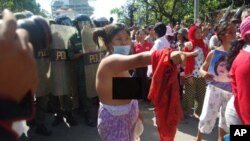 An unidentified female protester tore off her shirt at the demonstration Wednesday as riot police officers looked on. 