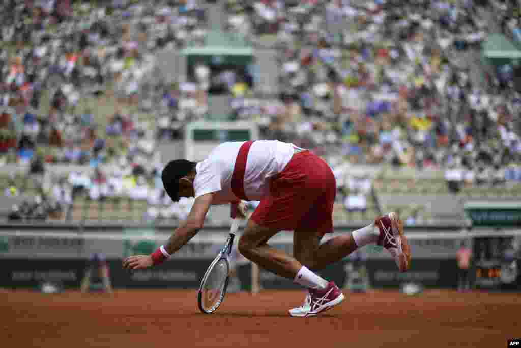 Serbia&#39;s Novak Djokovic stumbles during a point against Spain&#39;s Jaume Munar during their men&#39;s singles second round match on day four of The Roland Garros 2018 French Open tennis tournament in Paris, France.