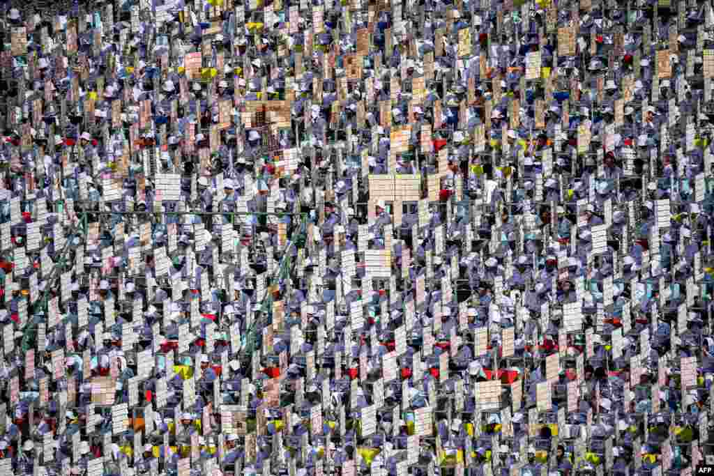 Young people hold signs for a mass display before a Holy Mass led by Pope Francis at the National Stadium in Bangkok, Thailand.