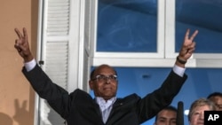 Le candidat présidentiel tunisien Moncef Marzouki rend le " V de la victoire " signe avant de donner un discours , après le second tour de l'élection présidentielle du pays , à Tunis , le dimanche 21 décembre 2014 .