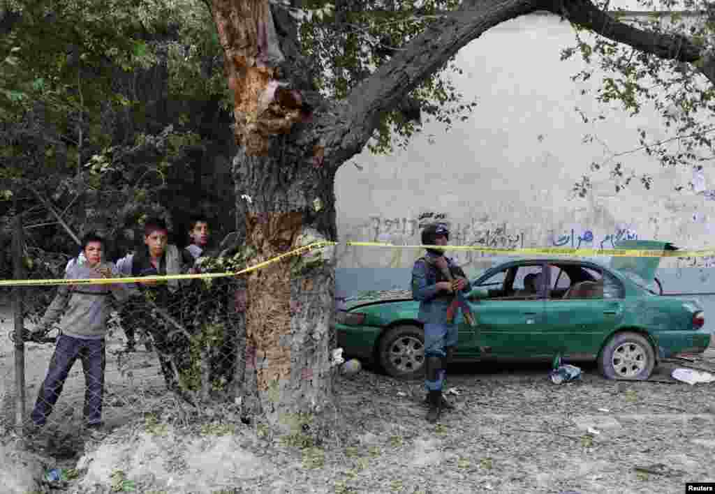 An Afghan police officer stands at the site of a suicide car bomb attack in Kabul, June 11, 2013.