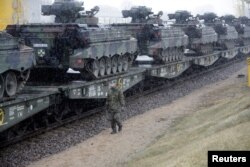 FILE - A German army soldier walks past Marder infantry fighting vehicles at the railway station in Sestokai, Lithuania, Feb. 24, 2017.