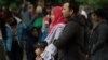 A Muslim family stands across the road from the Dean Street mosque when worshipers were gunned down in Christchurch on March 17, 2019. 