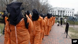 Protesters seeking closure of the Guantanamo Bay detention facility wear orange jumpsuits and black hoods as they demonstrate outside the White House, 11 Jan 2011