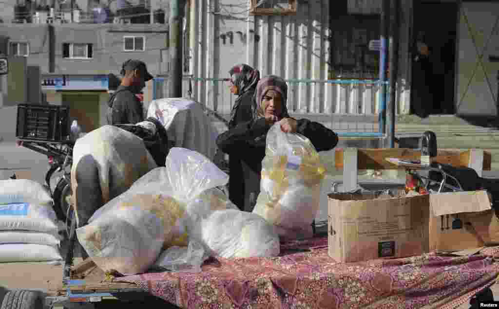 A woman carries a bag of food supplies that she received from a United Nations food distribution center in Khan Younis in the southern Gaza Strip July 31, 2014.